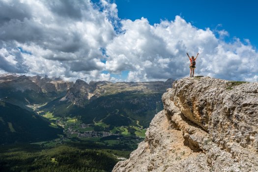 Person with arms raised over head standing on a mountain top.