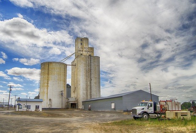 Rural agriculture industry with warehouse, trucks and grain silos.