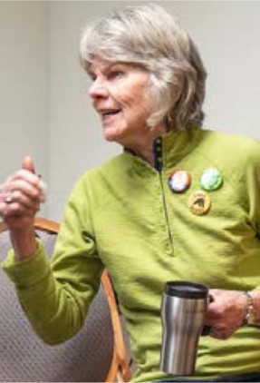 Photo of the author, Bobbi Righi. Gray medium-length hair and green top with multiple pins/buttons..