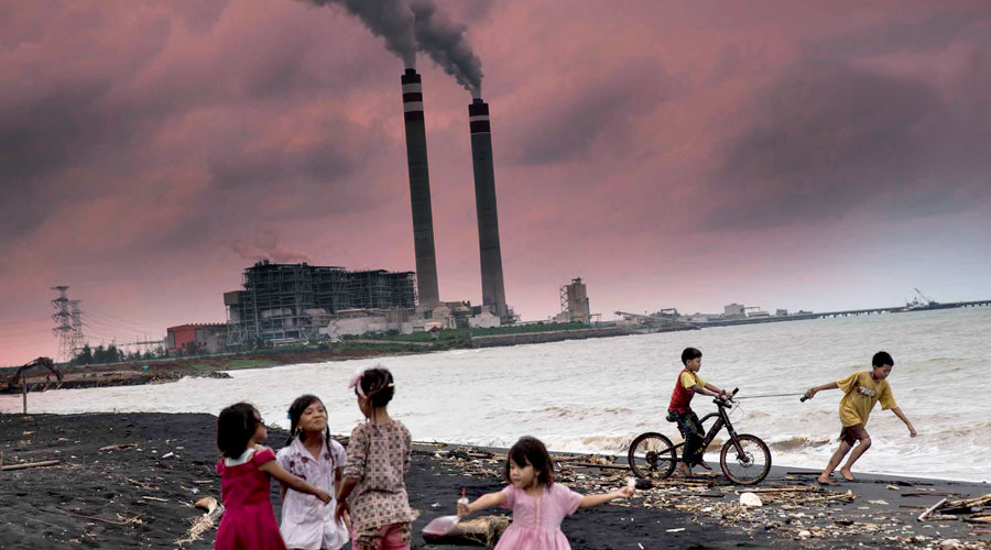 Smoking power plant behing kids playing on a littered beach.