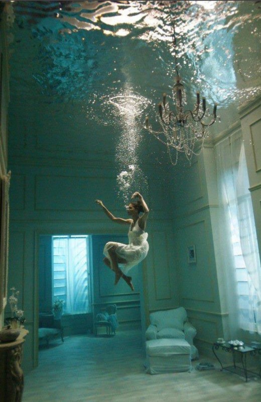 A woman floating in her livingroom full of water.