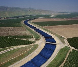 Solar panels covering a water aqueduct snaking among planted fields.