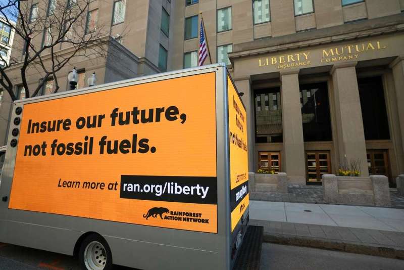 Insure our future, not fossil fuels. On yellow sides of truck box, in front of Liberty Mutual.