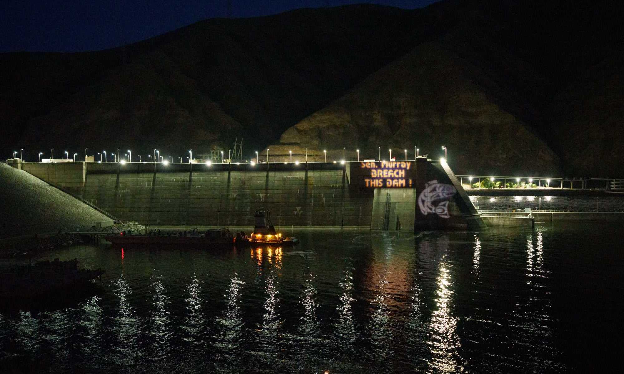 Snake River dam showing protest projection at night. Sen. Murray, Breach this Dam!