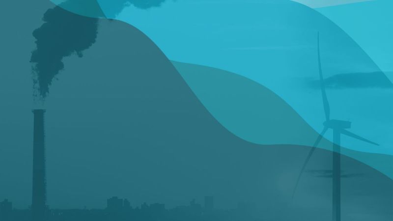 Smokestack and Windmill against blue hills.