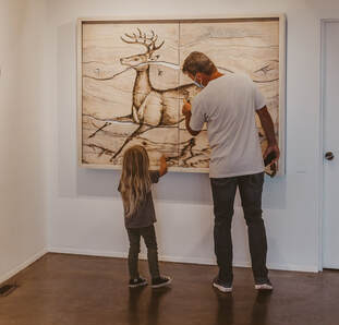 Father and daughter examining a painting.