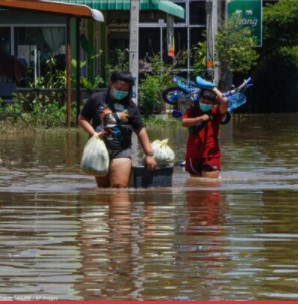 People wading through flooded area with their belongings