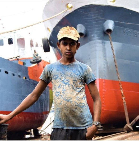 Youth standing in front of large ships