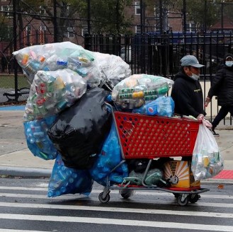 Man with grocery cart overflowing with giant bags of cans.